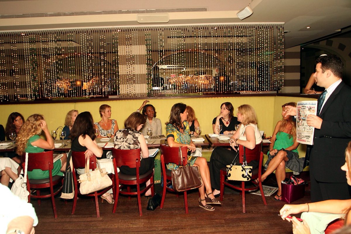 The original DIVAS WHO DINE gathered around a long restaurant table in Manhattan.